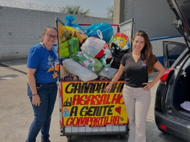 Campanha do agasalho do CEPIS, com carrinho cheio de doações e cartaz feito à mão.